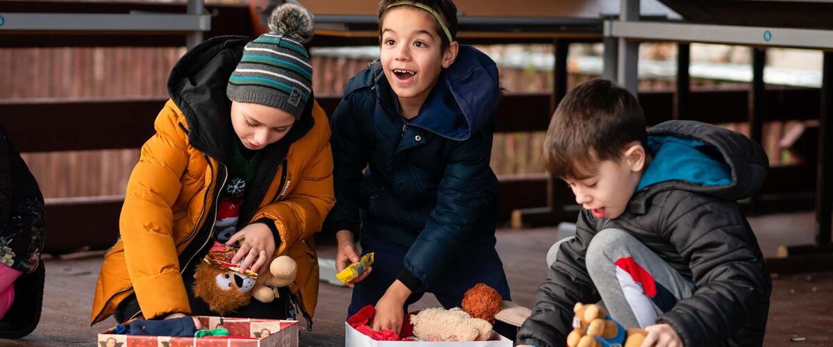 Drei Jungen packen ihre Geschenke voller Begeisterung aus