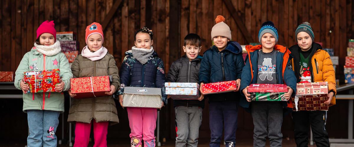 Mehrere Kinder freuen sich über die Weihnachtspäckchen der humedica-Aktion Geschenk mit Herz
